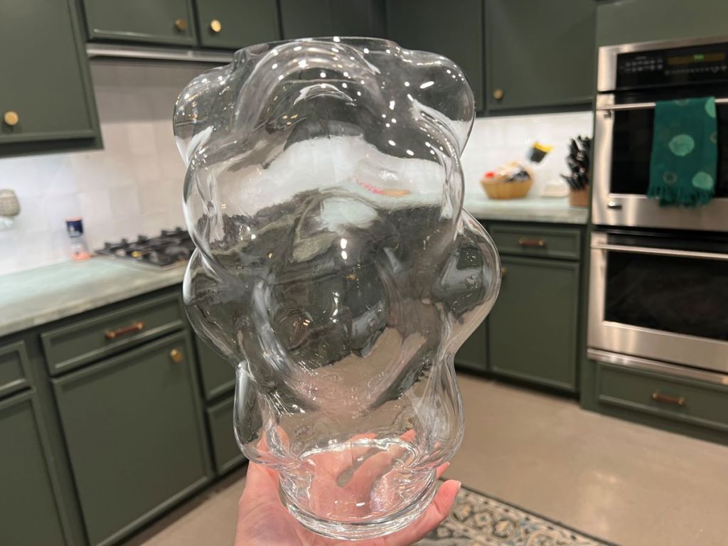 Hand holding a clear vase that looks like it has bubbles in it