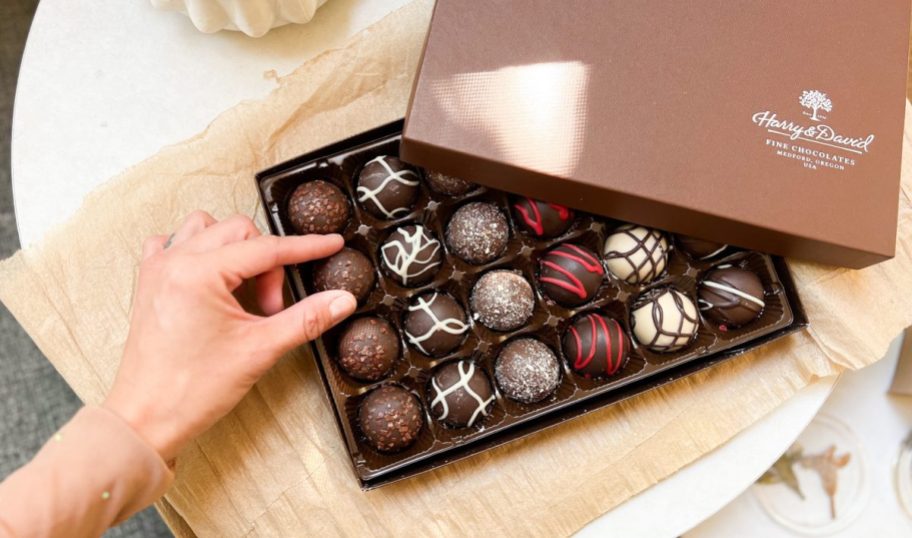 hand taking a truffle out of a Harry and David Signature Truffles box