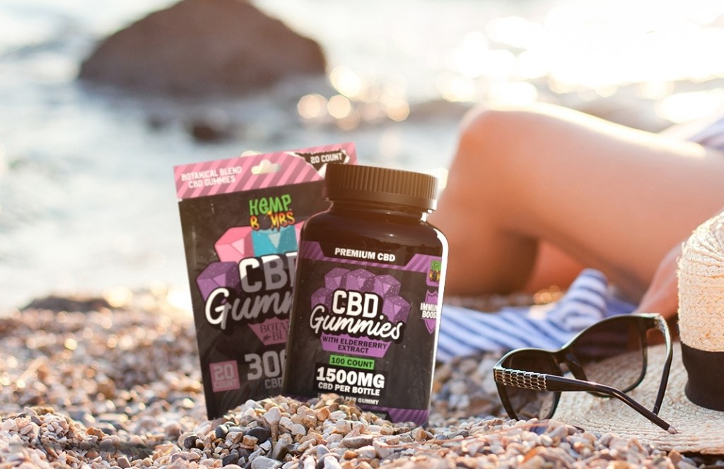 Bottle and bag of Hemp Bombs Immunity Gummies on a beach next to a person in a beach chair