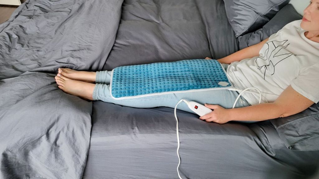 Woman sitting in bed with a heating pad on her legs