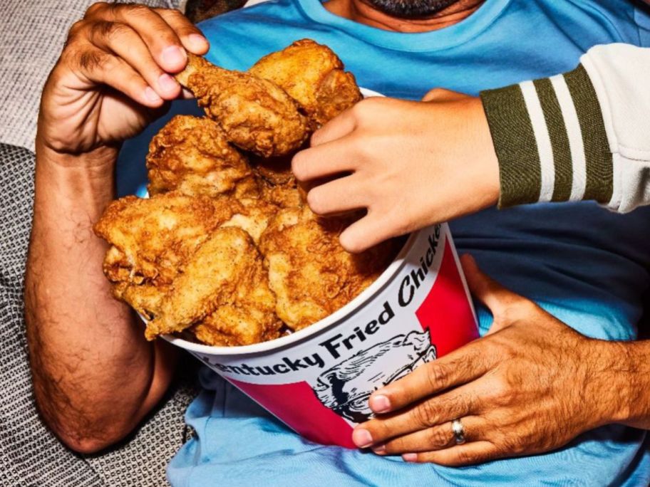 two hands taking chicken KFC Chicken Bucket