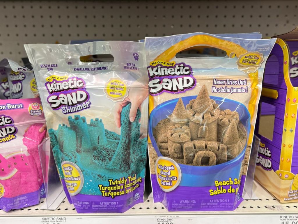 teal shimmer Kinetic Sand 2lb bag and brown Kinetic Sand on store shelf