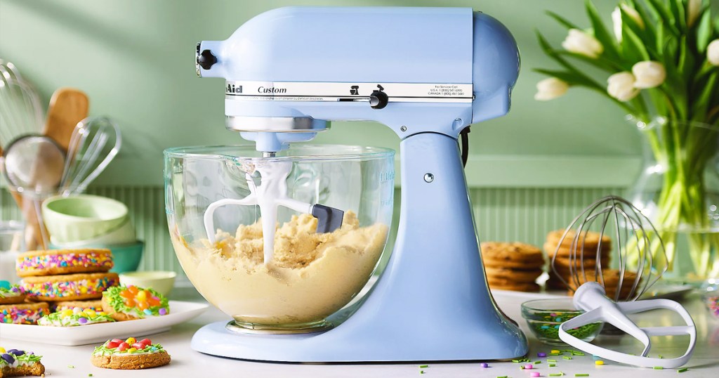 light blue kitchenaid mixer with glass bowl and attachments on counter
