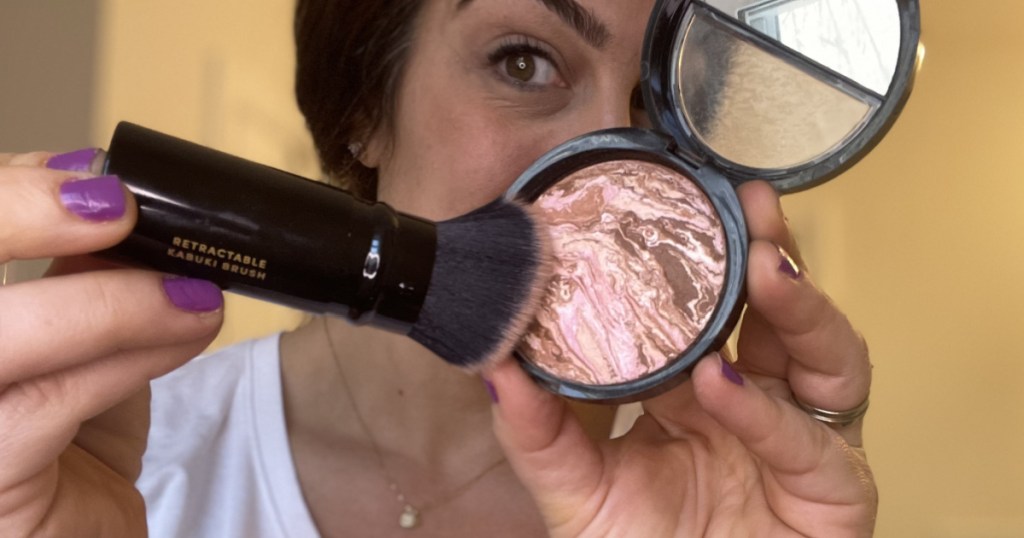 woman with Laura Geller balancing foundation and brush