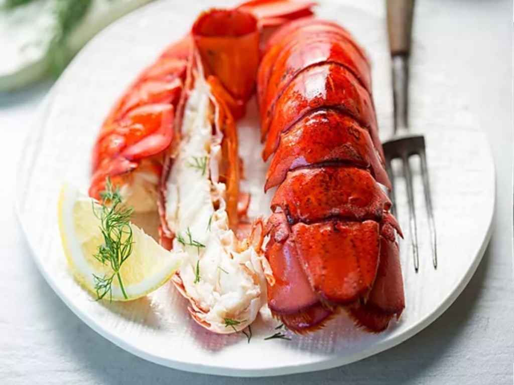 red lobster tail on plate with lemon and garnish