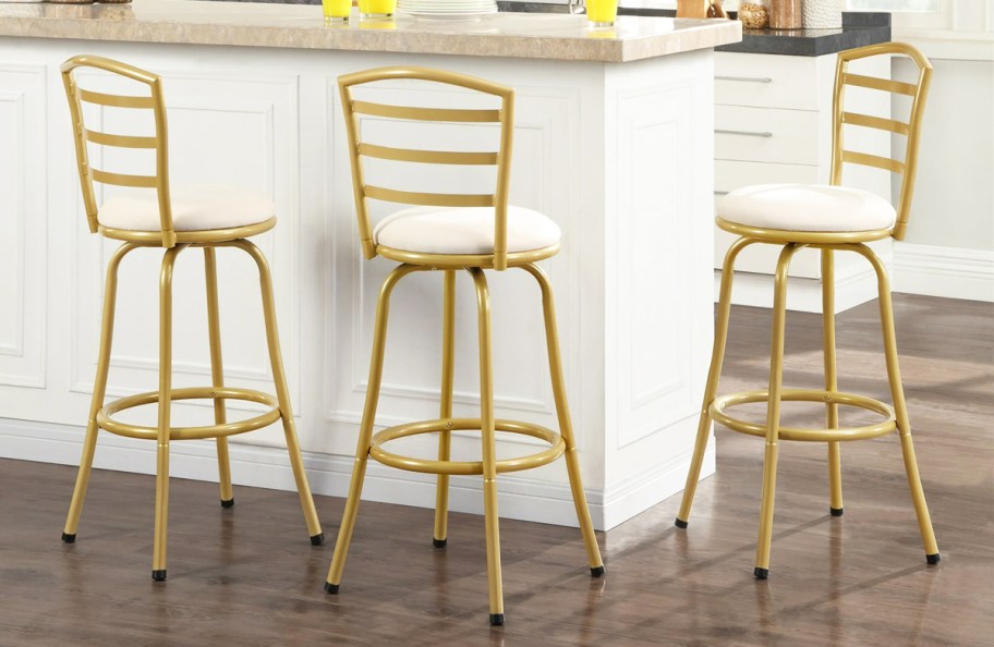 three gold and white barstools at kitchen counter