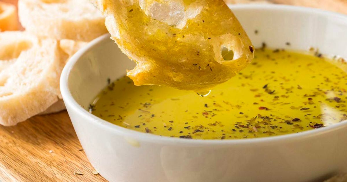 A hand dipping a costini into melted butter seasoned with McCormick Mediterranean Herb and salt blend