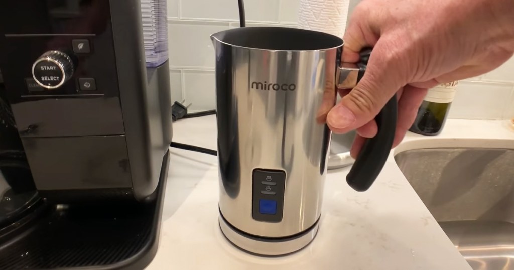hand grabbing a stainless steel milk frother