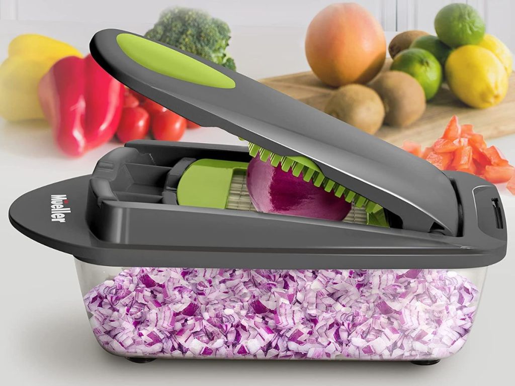 Vegetable slicer with an onion on top and sliced onions inside of it.