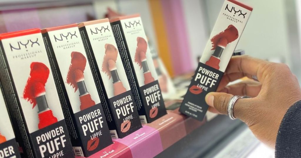 A hand grasping a box of lip stick in a store