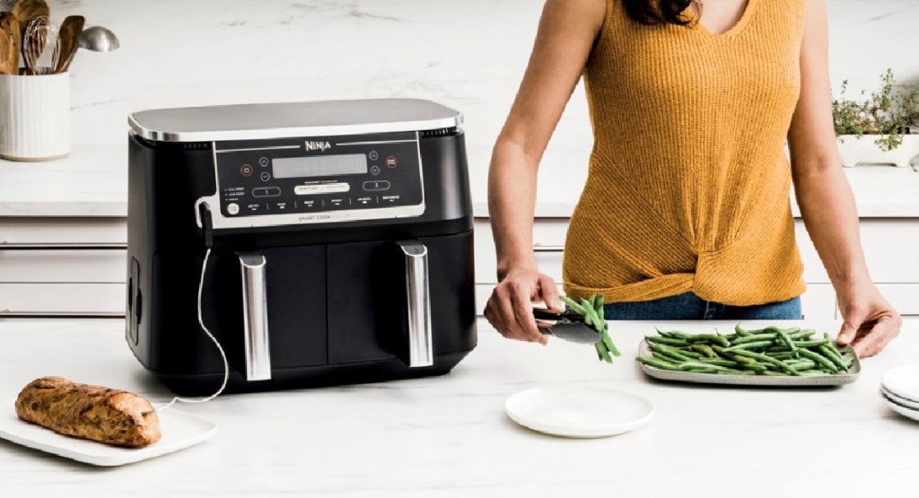 Ninja double baskets air fryer with meat and woman picking green beans on counter