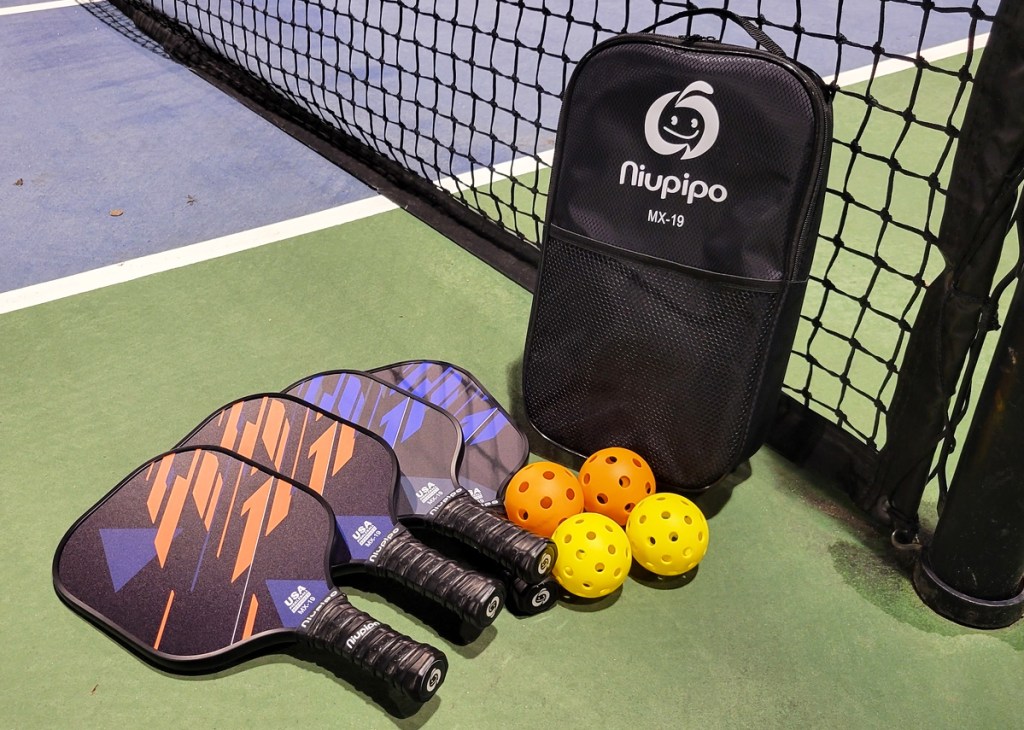 pickleball paddles, balls, and bag on court