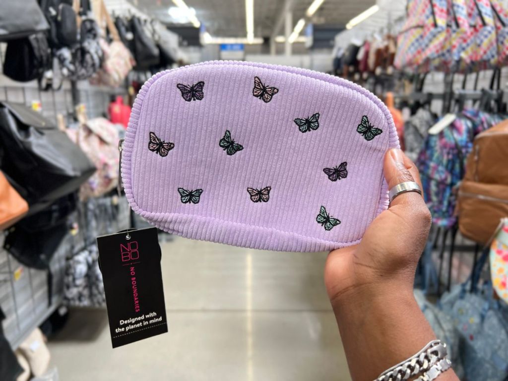 A hand holding a purple fanny pack with butterflies on it 