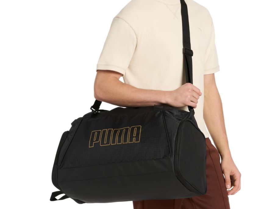hand holding PUMA Unisex Evercat Accelerator Duffel Bag in black and gold