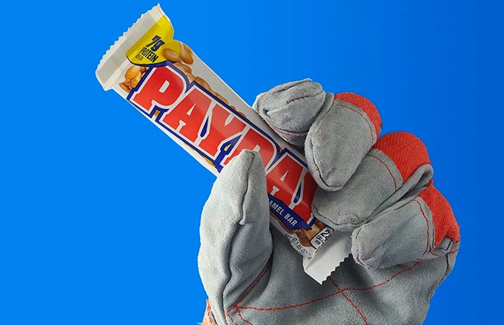 Payday bar being held by a hand in a work glove