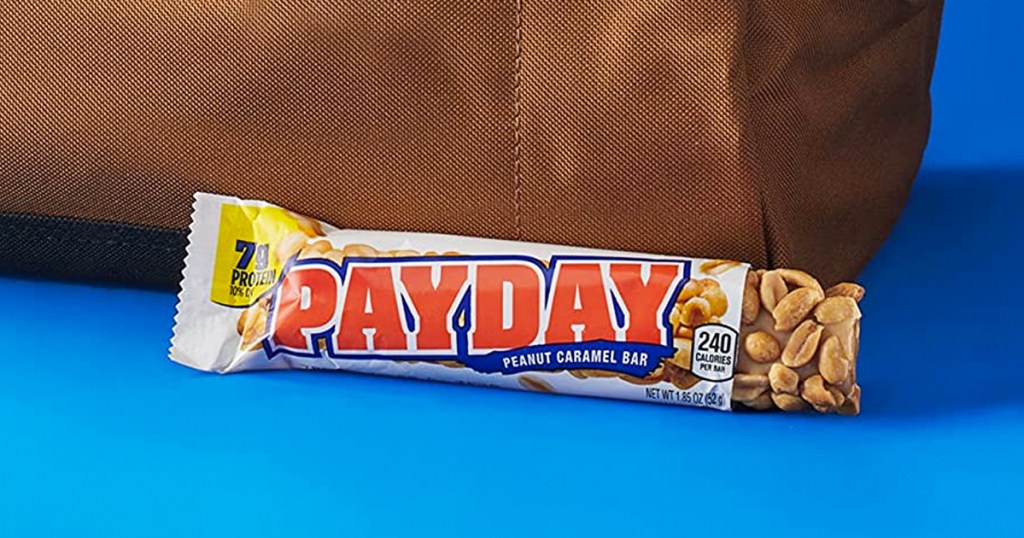 unwrapped payday candy bar leaning against brown bag
