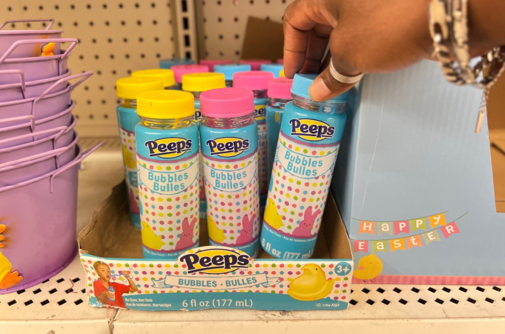 Woman taking a container of Peeps Bubbles off a Dollar Tree shelf