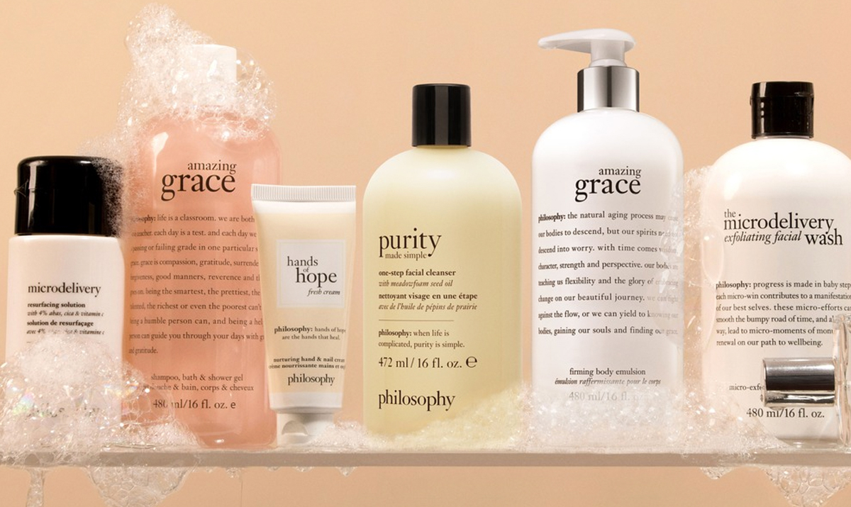 various philosophy products covered in soap suds on glass shelf 