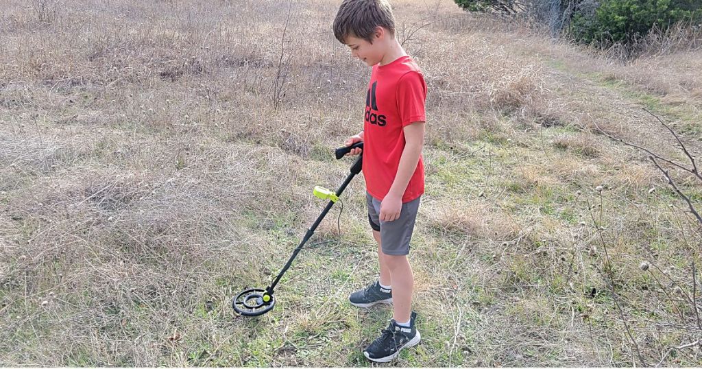 boy walking through woods using kids metal detector