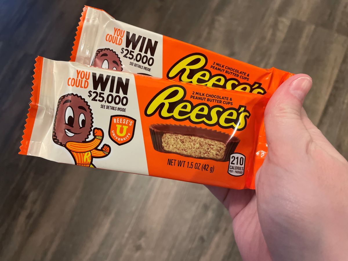 hand holding two packs of Reese's Peanut Butter Cups