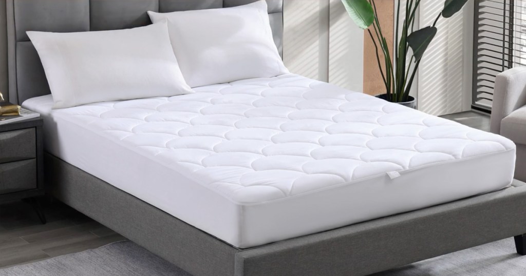 white waterproof mattress pad on a bed with two pillows