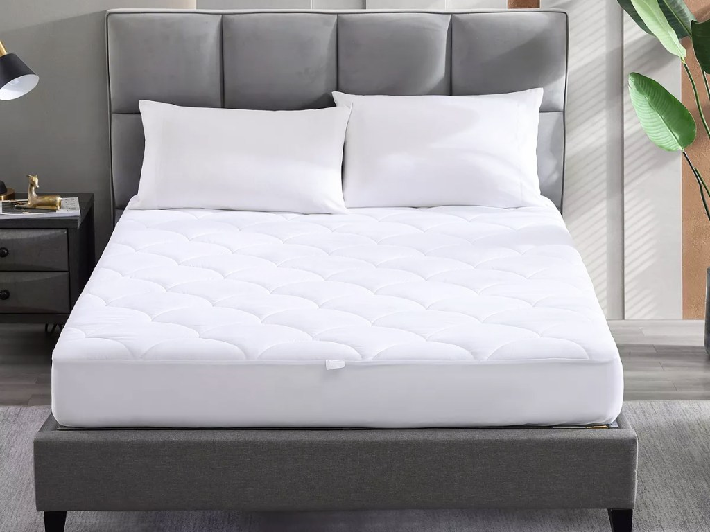 white waterproof mattress pad on a bed with two pillows