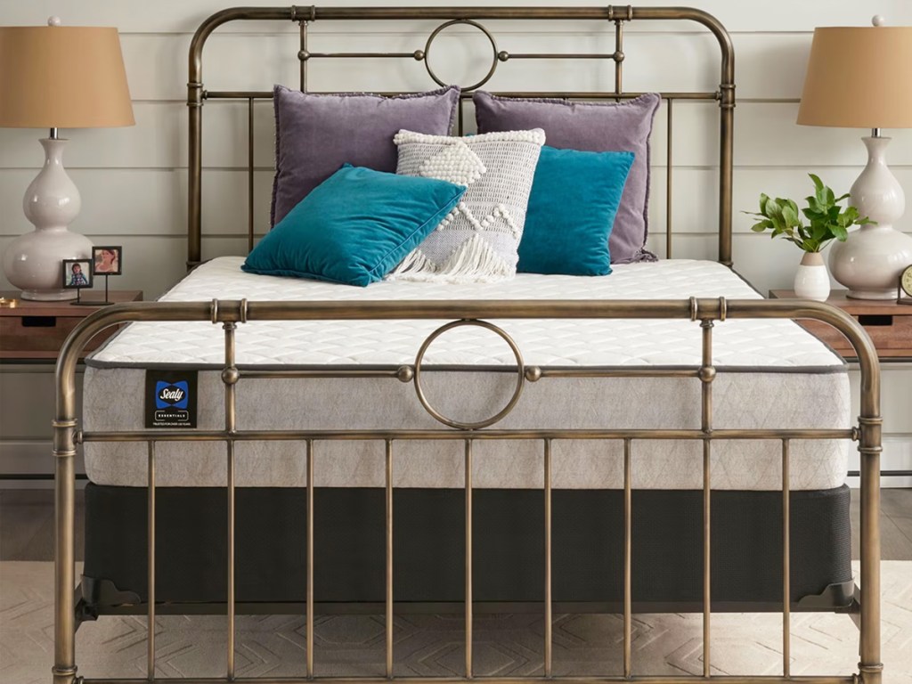 mattress on a metal bed frame with throw pillows on top