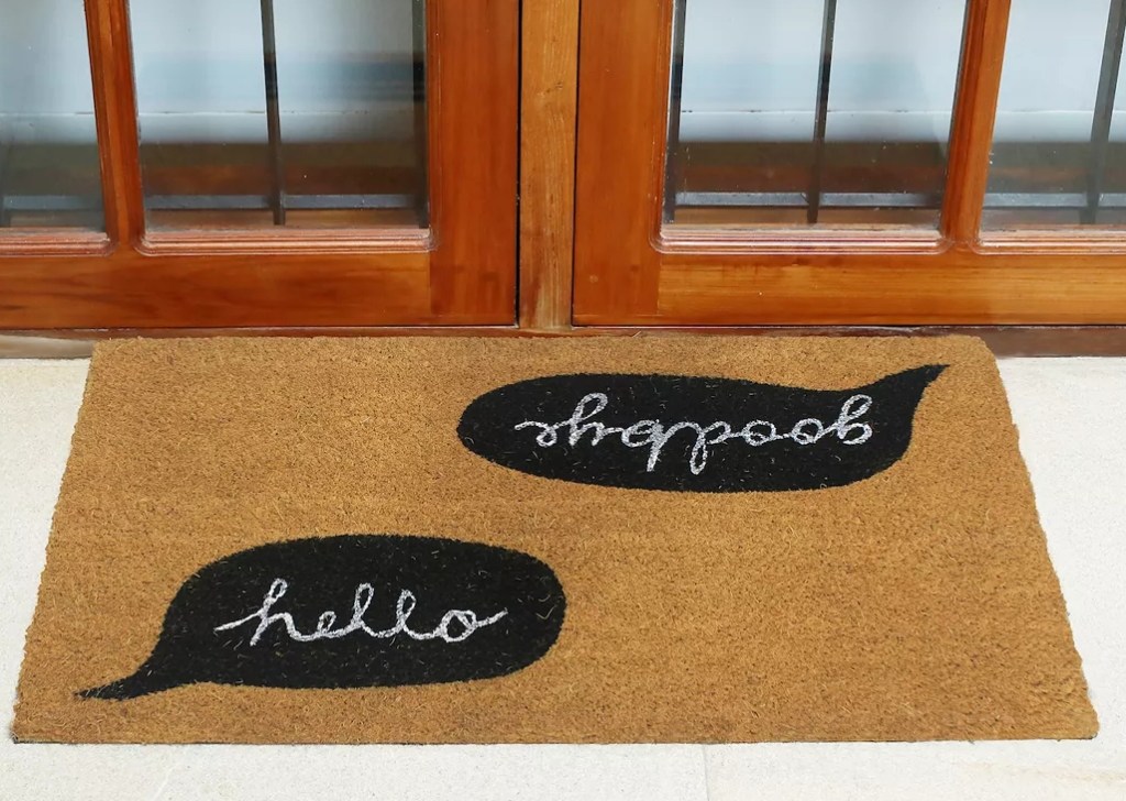 doormat by a door that says hello on one side and goodbye on the other side