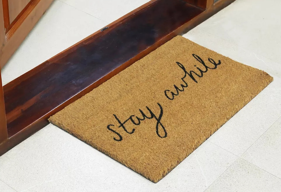 doormat by a door that says Stay Awhile