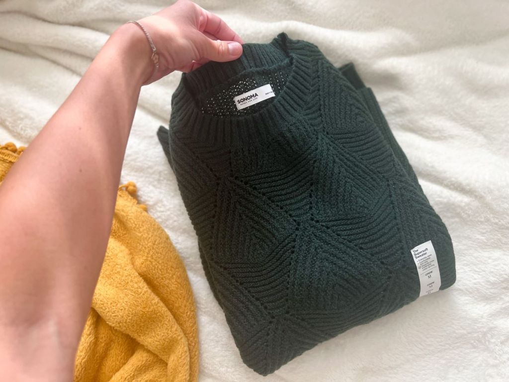 hand holding the top of a folded sweater