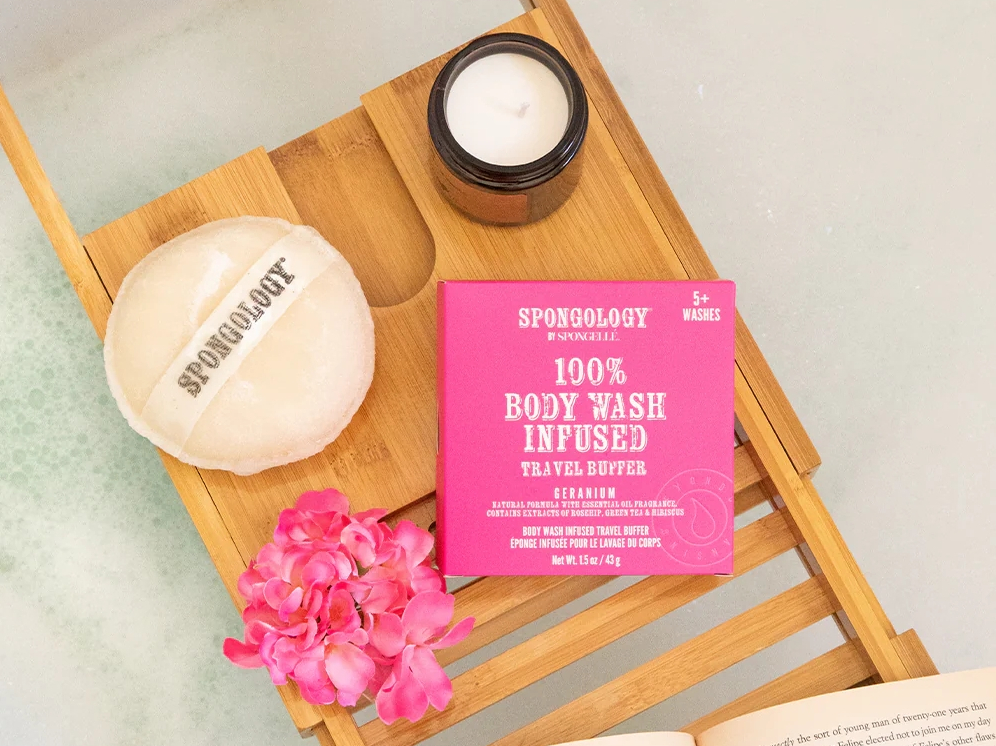 Body sponges on a tray over a bathtub with a geranium