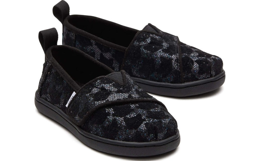 Pair of solid black TOMS shoes with black lace on them.