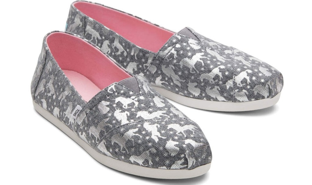 Pair of grey TOMS with unicorns printed on them in silver and a pink lining.