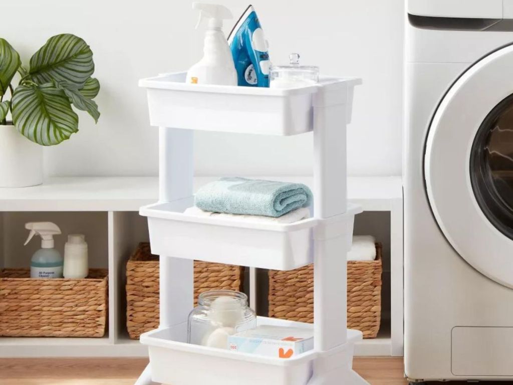 Three tier cart with laundry supplies on it next to a washer