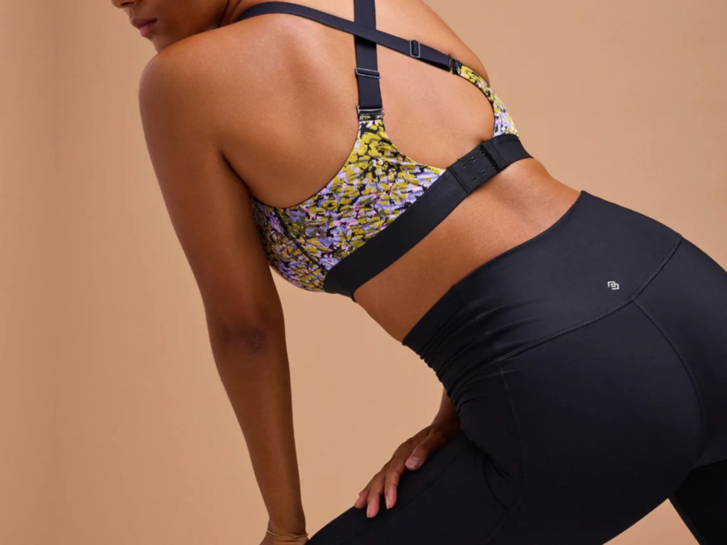 woman stretching in third love sports bra with flower pattern and black leggings