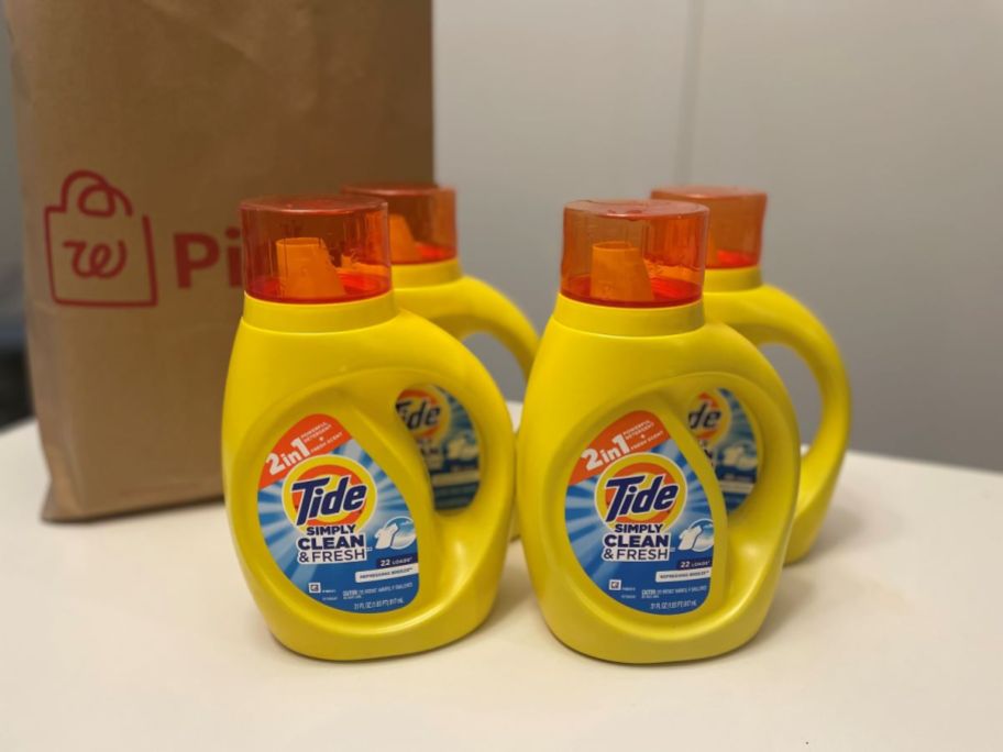 Four bottles of Tide Simply next to a Walgreens bag