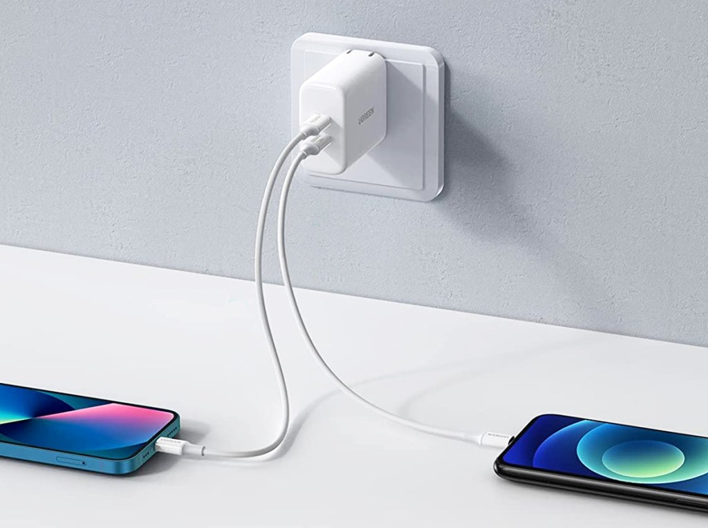 two phones plugged into white charging block