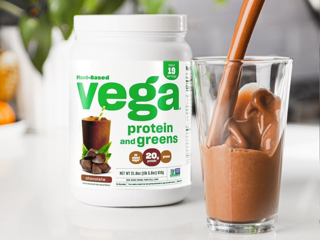 chocolate protein shake next to container of vega protein powder