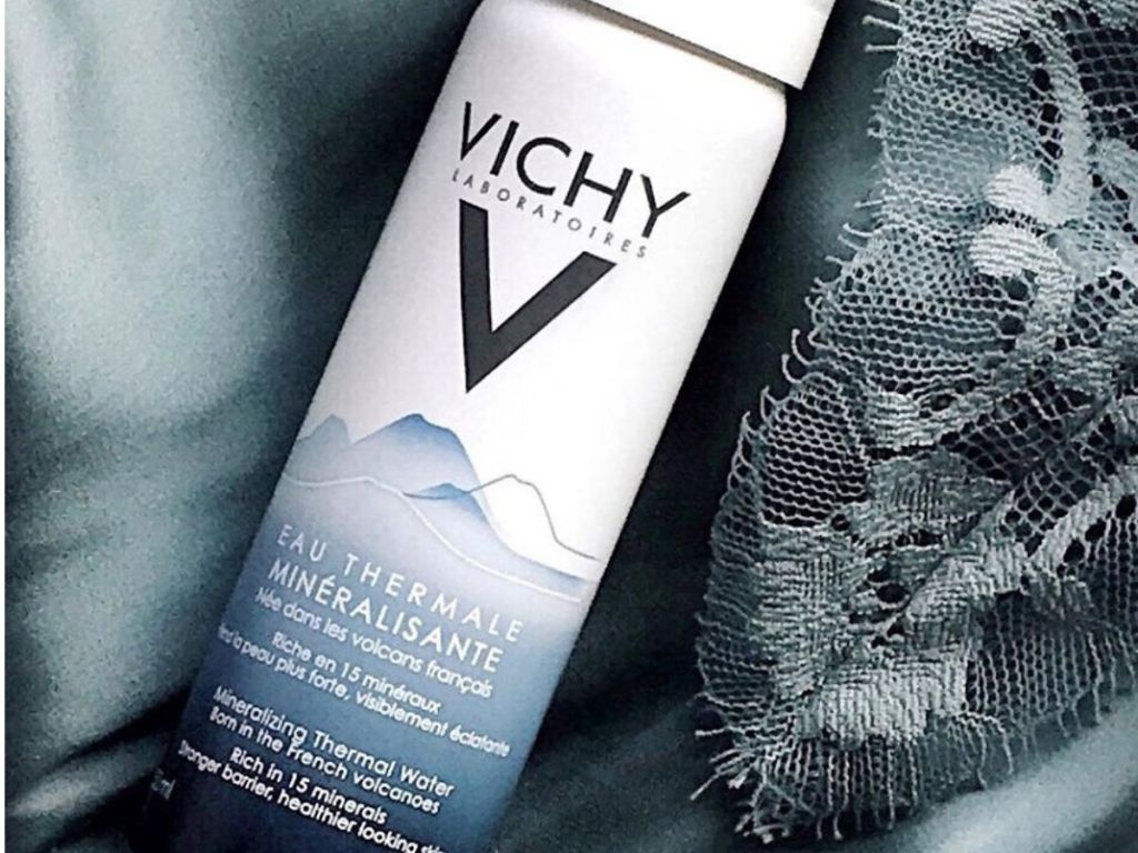 Bottle of Vichy spa water laying on silk and lace