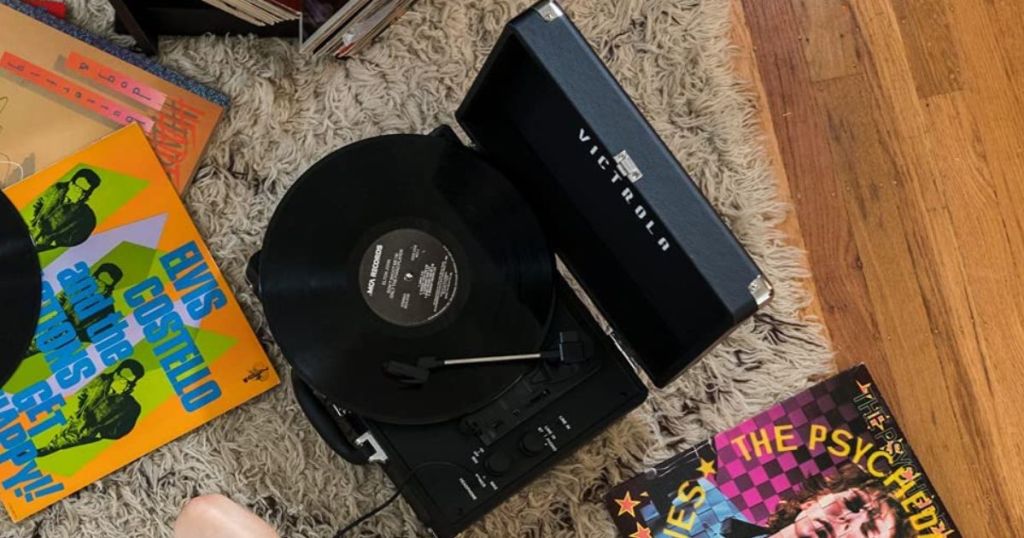 Record player sitting on a rug with records around it
