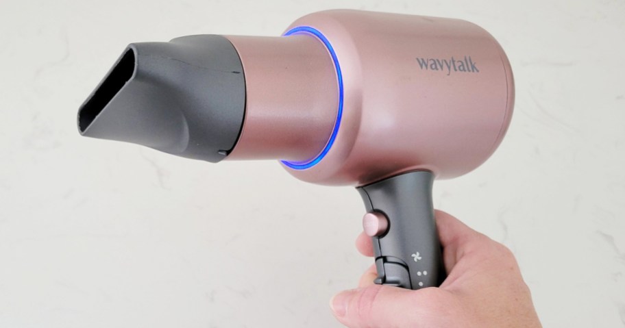 hand holding up pink and grey hair dryer