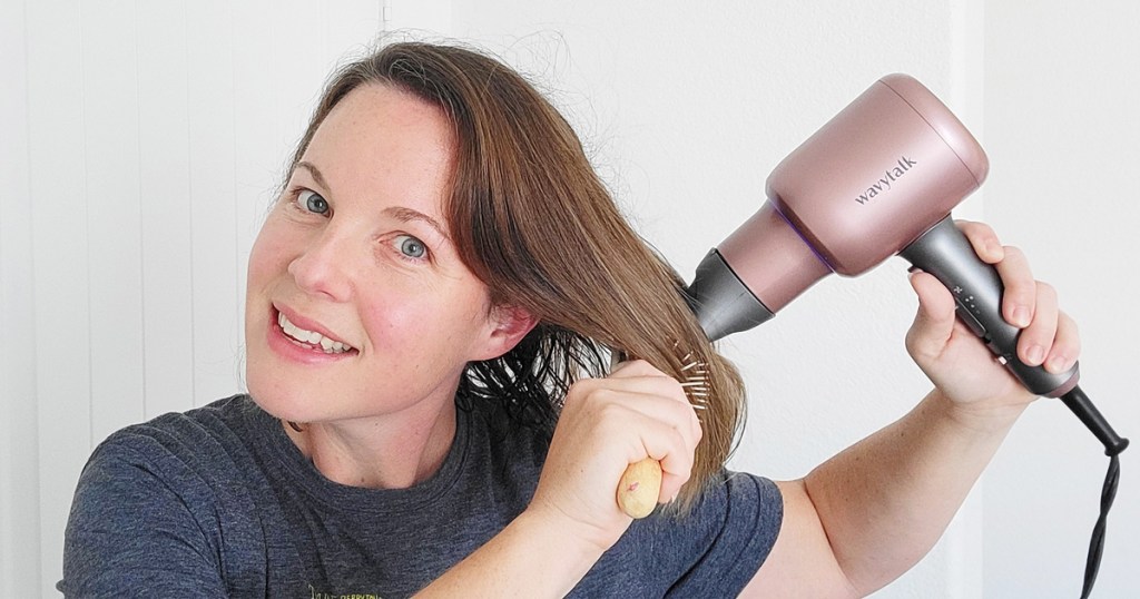 woman using pink hair dryer on her hair