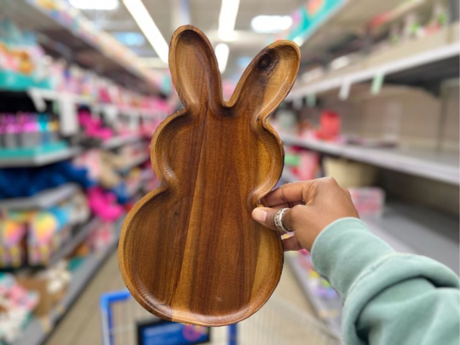 a womans hand holding a wooden bunny shaped serving tray