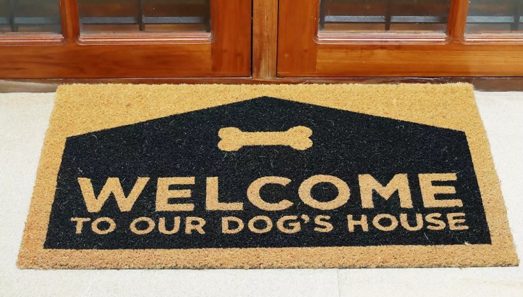 Fußmatte neben einer Tür, auf der Willkommen im Haus unseres Hundes steht