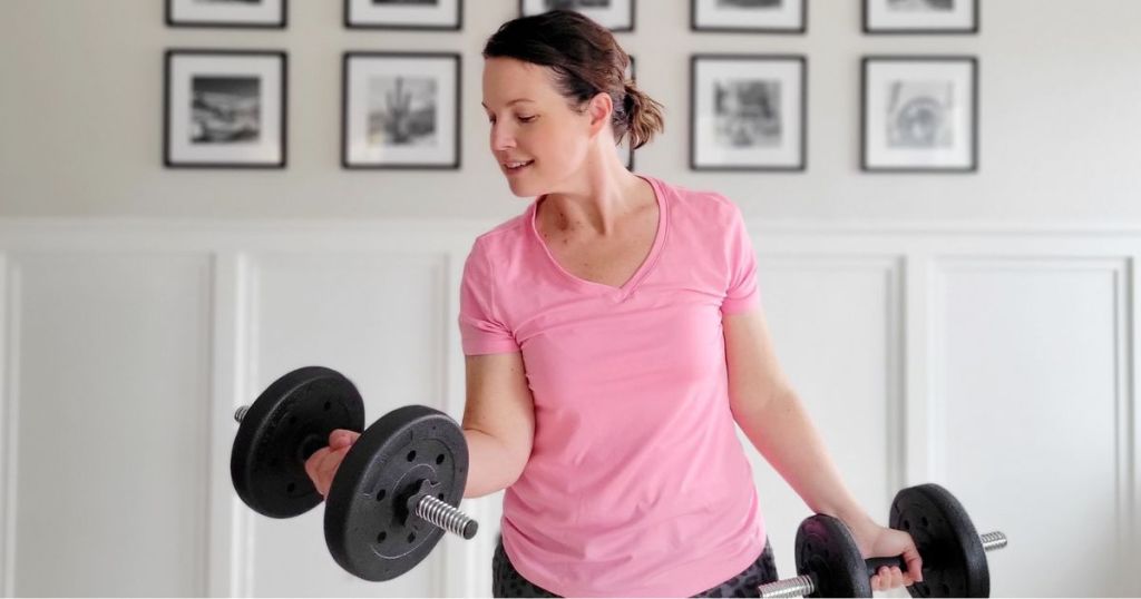woman doing curls with heavy dumbbells in her living room