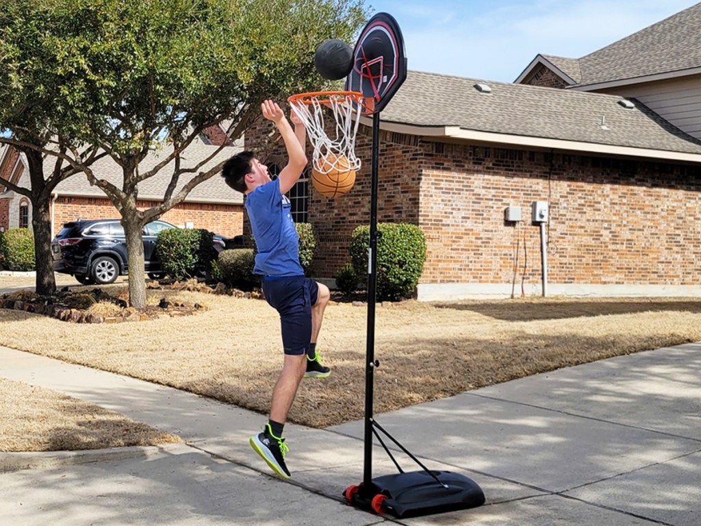 boy dunking ball into basketball hoop