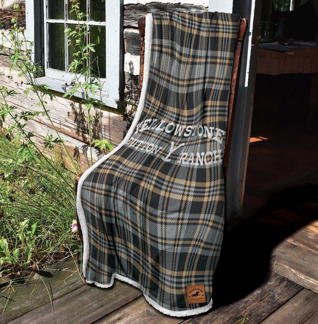 Large plaid throw blanket draped over a chair outside of a log cabin