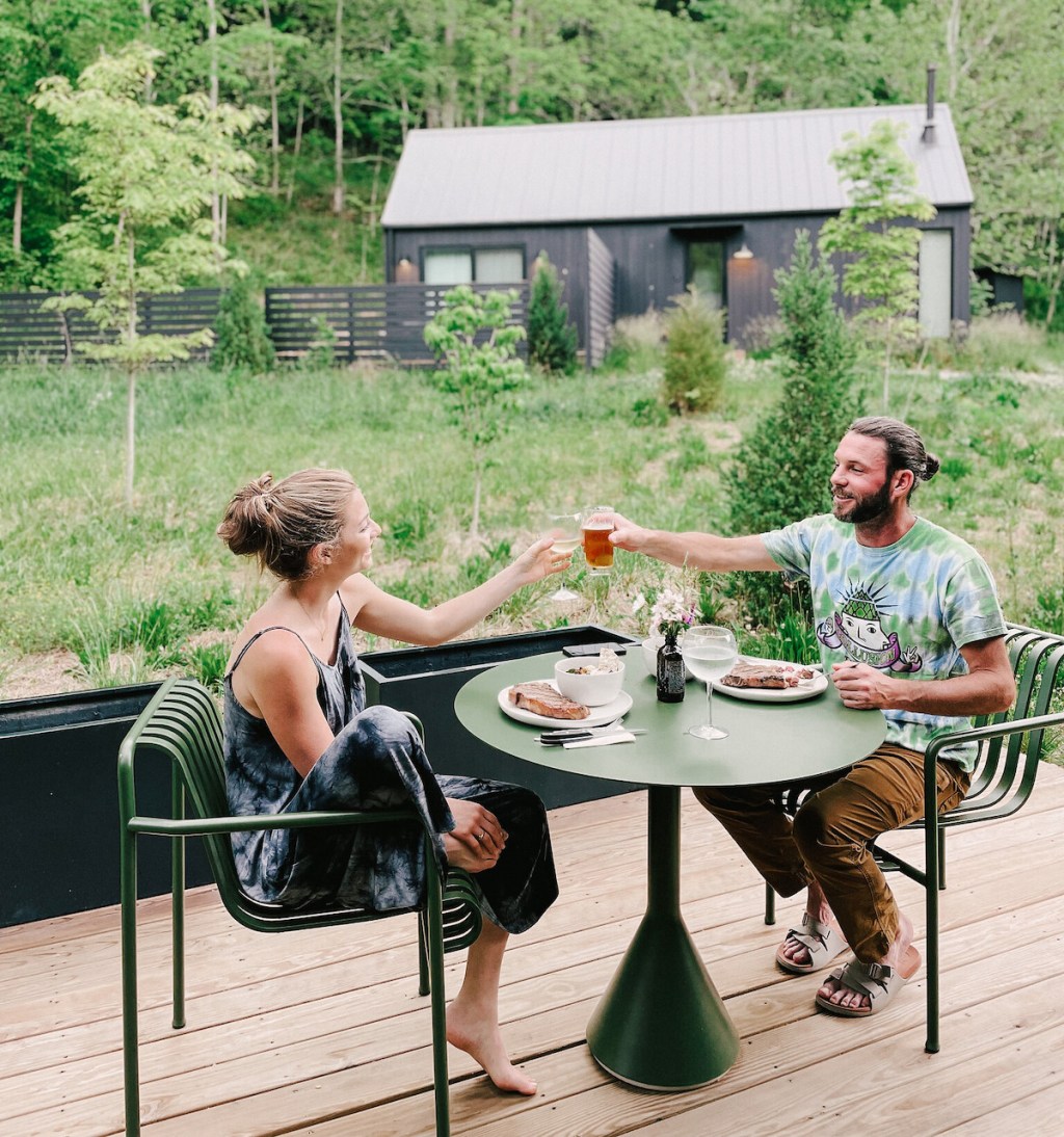 couple toasting with drinks at outside dining table with airbnb essentials