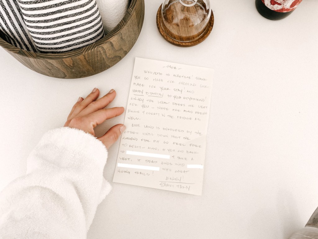 hand holding side of handwritten note on white countertop for airbnb essentials