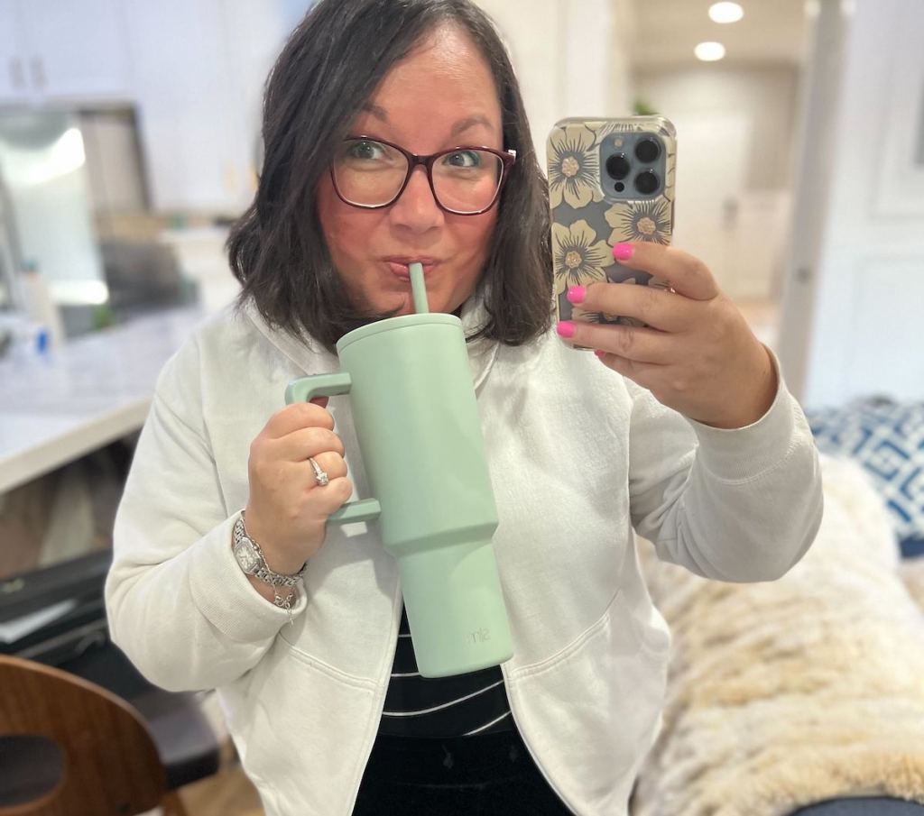 woman sipping from blue simple modern tumbler in mirror